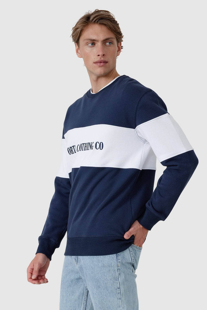 Male model wearing navy crew neck sweater with white middle panel and navy embroidered ORTC Clothing co