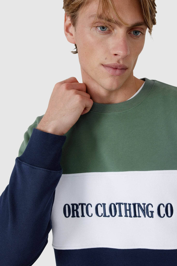 Male model wearing Crew neck sweater with olive top , white middle panel with embroidered ortc clothing co and navy bottom panel