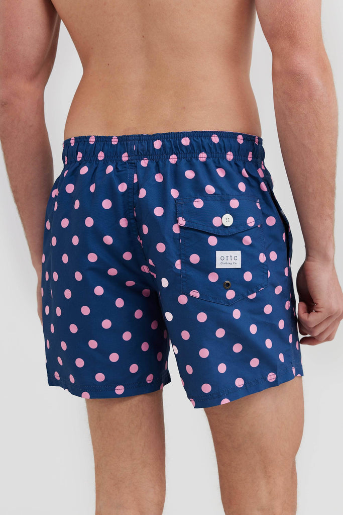 Back of navy board shorts with pink polka dots, with back pocket and ortc logo