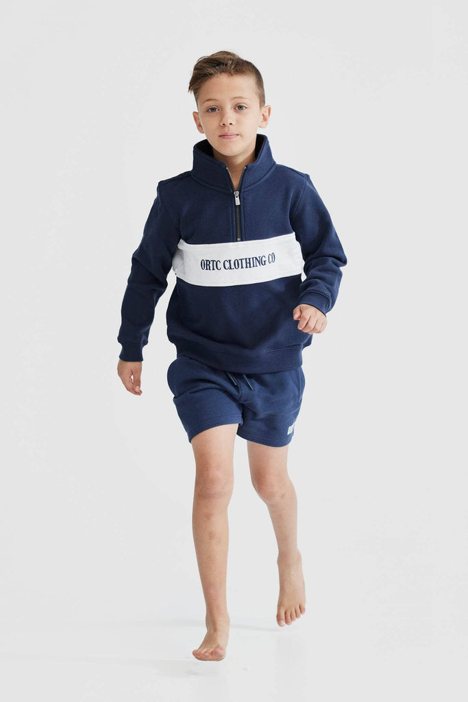 Child model wearing navy quarter zip with with white middle panel with navy ortc embroidered clothing co