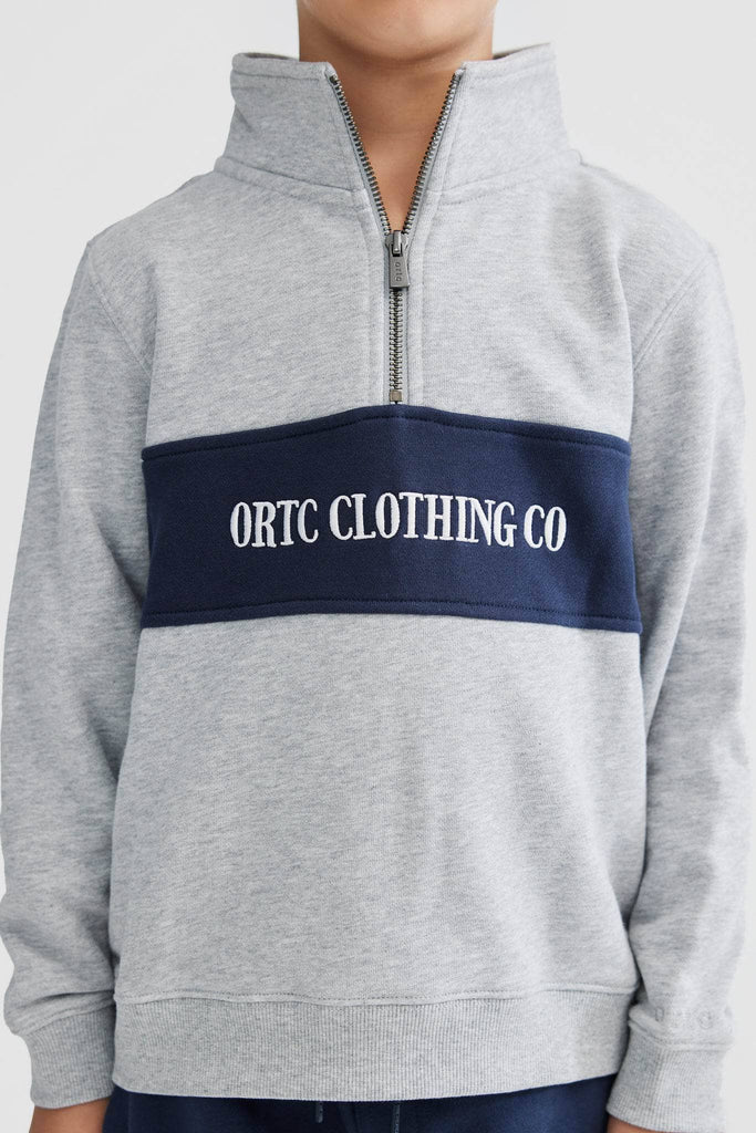 Child model wearing grey quarter zip with navy middle panel and white embroidered ortc clothing co
